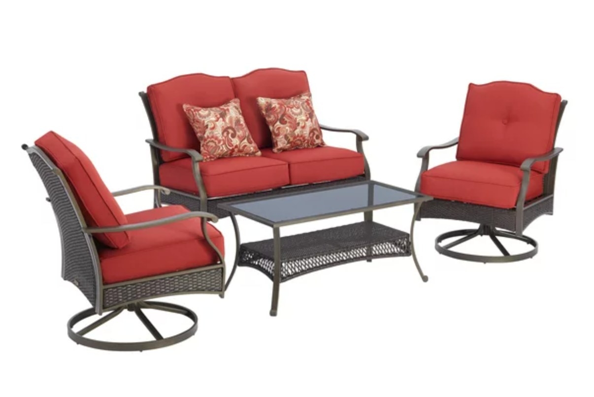 the red cushioned chairs, sofa, and glass topped wicker coffee table