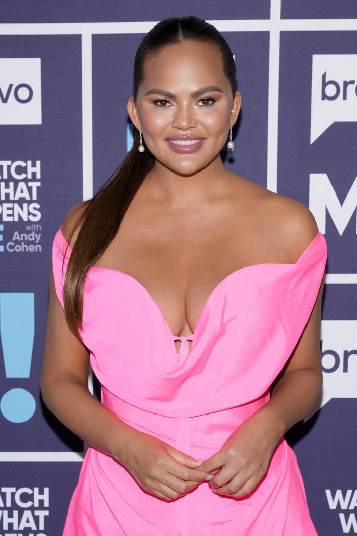 Chrissy Teigen poses at &#x27;Watch What Happens Live&#x27; in a bright pink dress