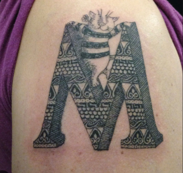tattoo of a cat on a letter &quot;M&quot;