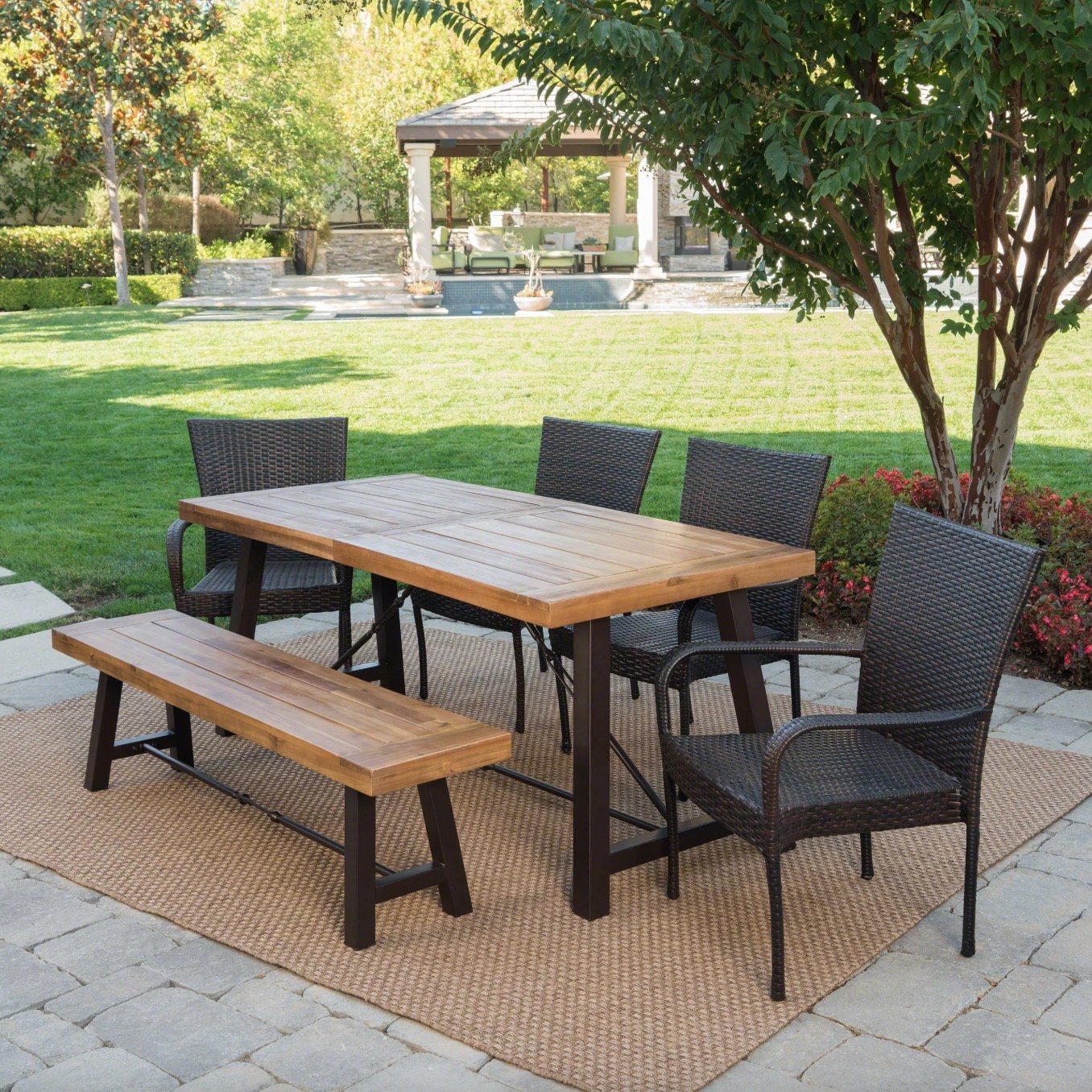 the light wood table and bench with dark wicker chairs in a decorated patio space