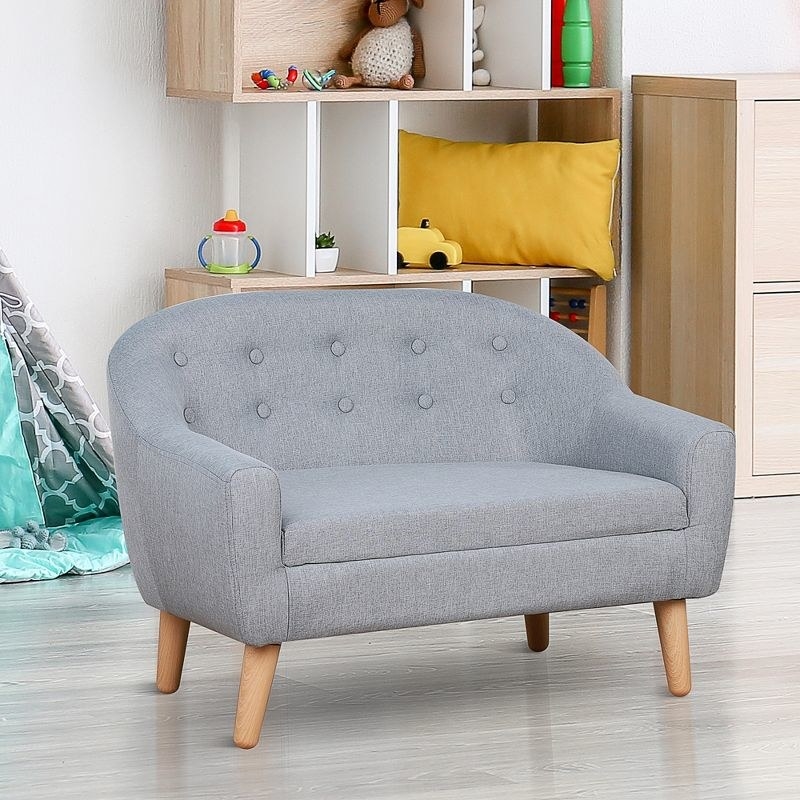 a small grey couch in front of a shelf with toys