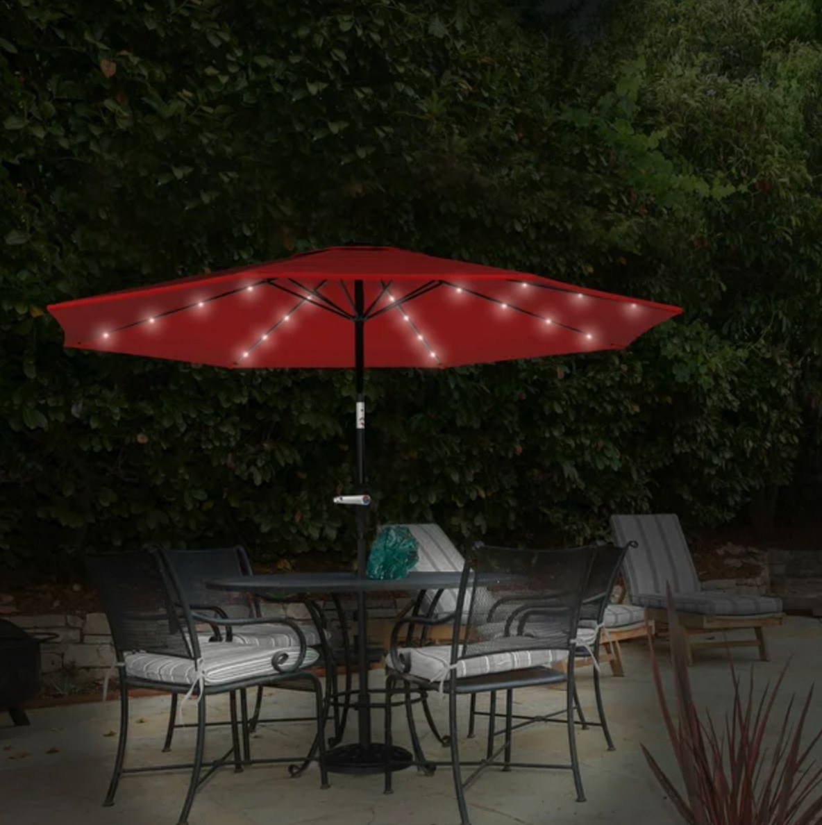 the red umbrella with lights on the underside over a dining table on a patio
