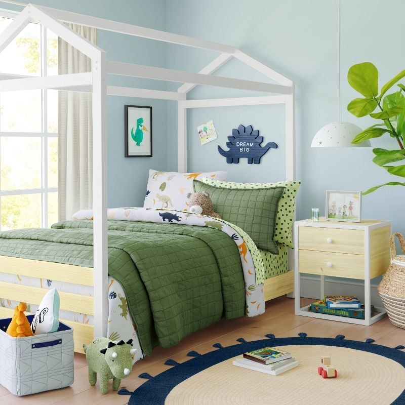 a child's bedroom fully decorated with beddings, toys, and a wooden nightstand