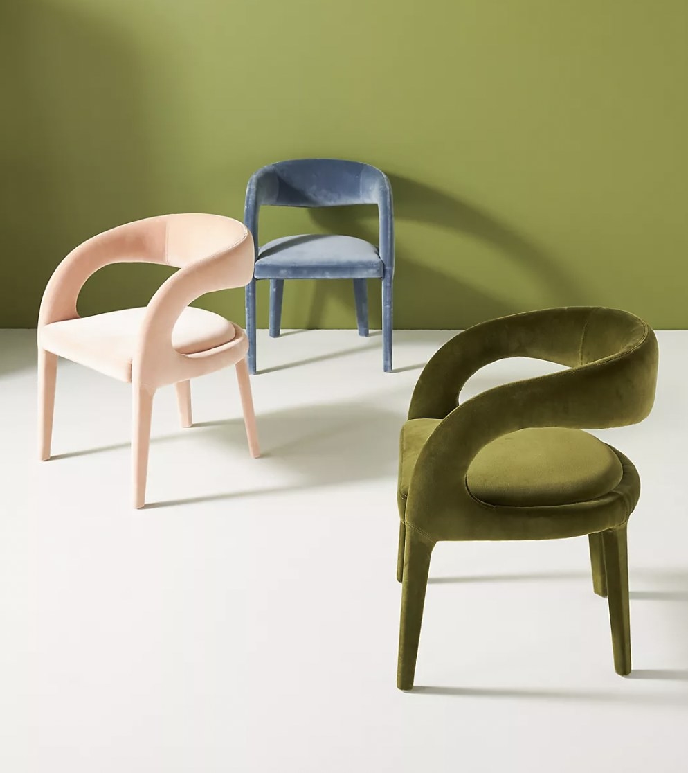 A blue chair, pink chair, and green chair spread out in room