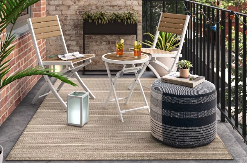 The black and gray pouf used as a table on a patio