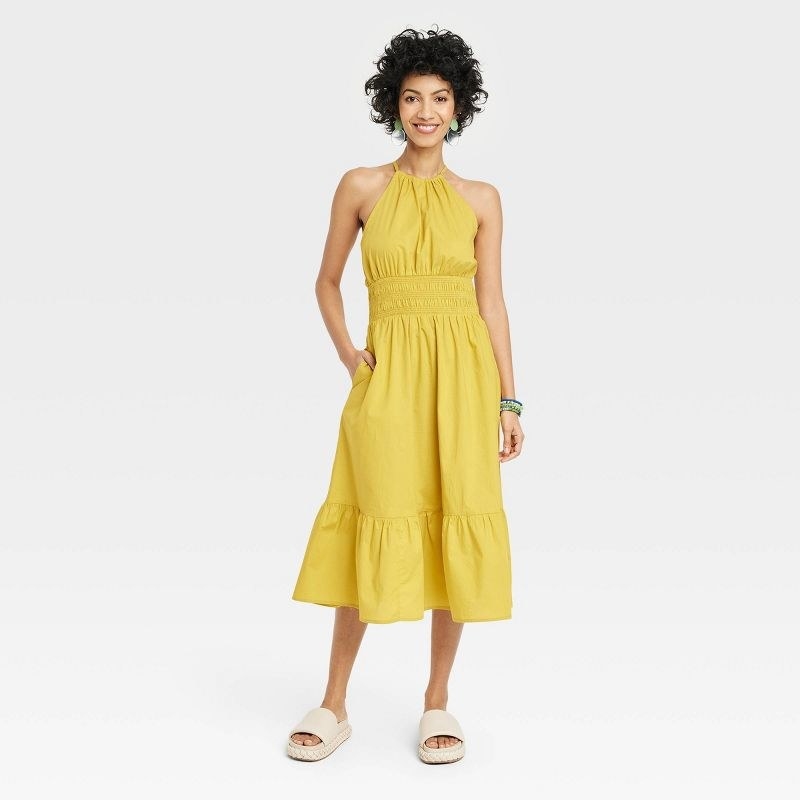 A model wearing a yellow dress with white sandals