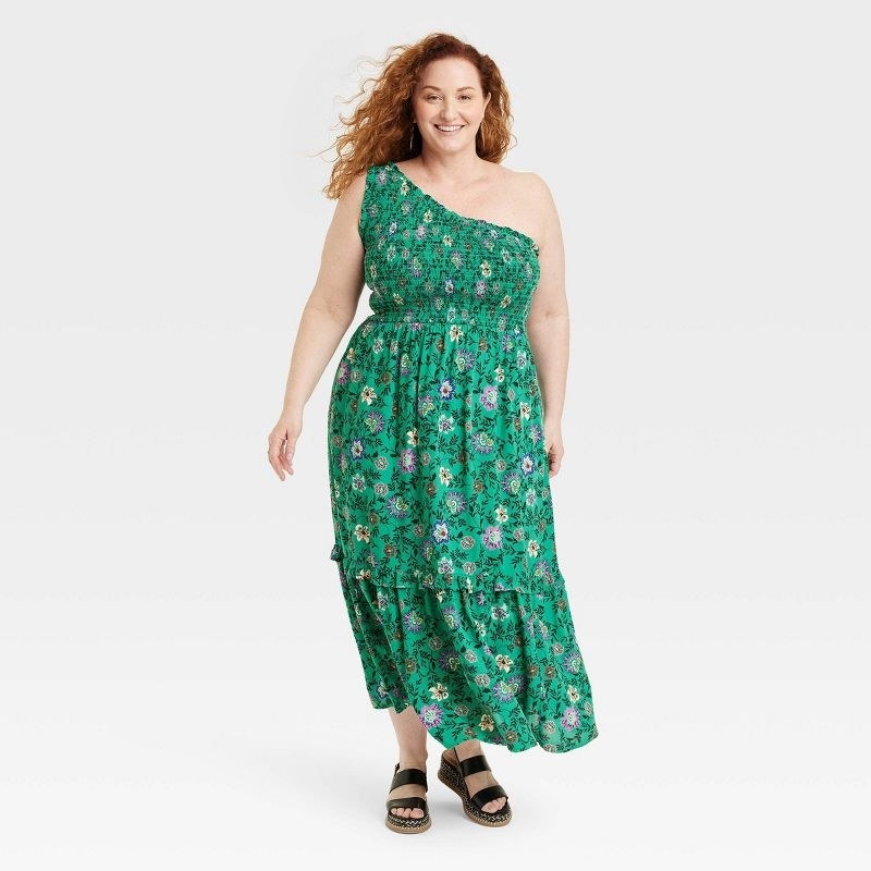 Model wearing green dress with floral print and black sandals