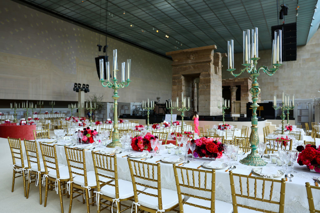 Long tables with red and pink camellias centerpieces and gold chairs