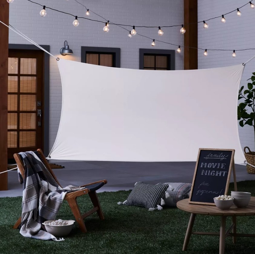The outdoor movie screening kit in the backyard with a chair, throw pillows, and a sign