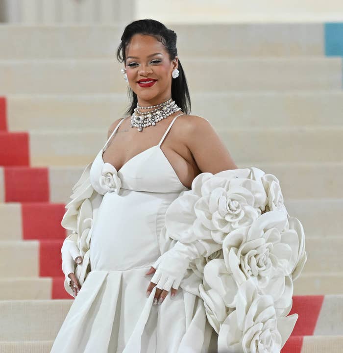 Rihanna wearing a white dress with a long white coat full of big camellias