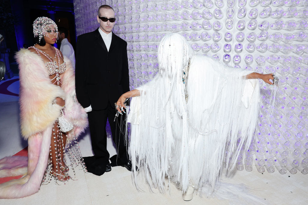Erykah Badu does a curtsy in her white, long, thinly drapped outfit