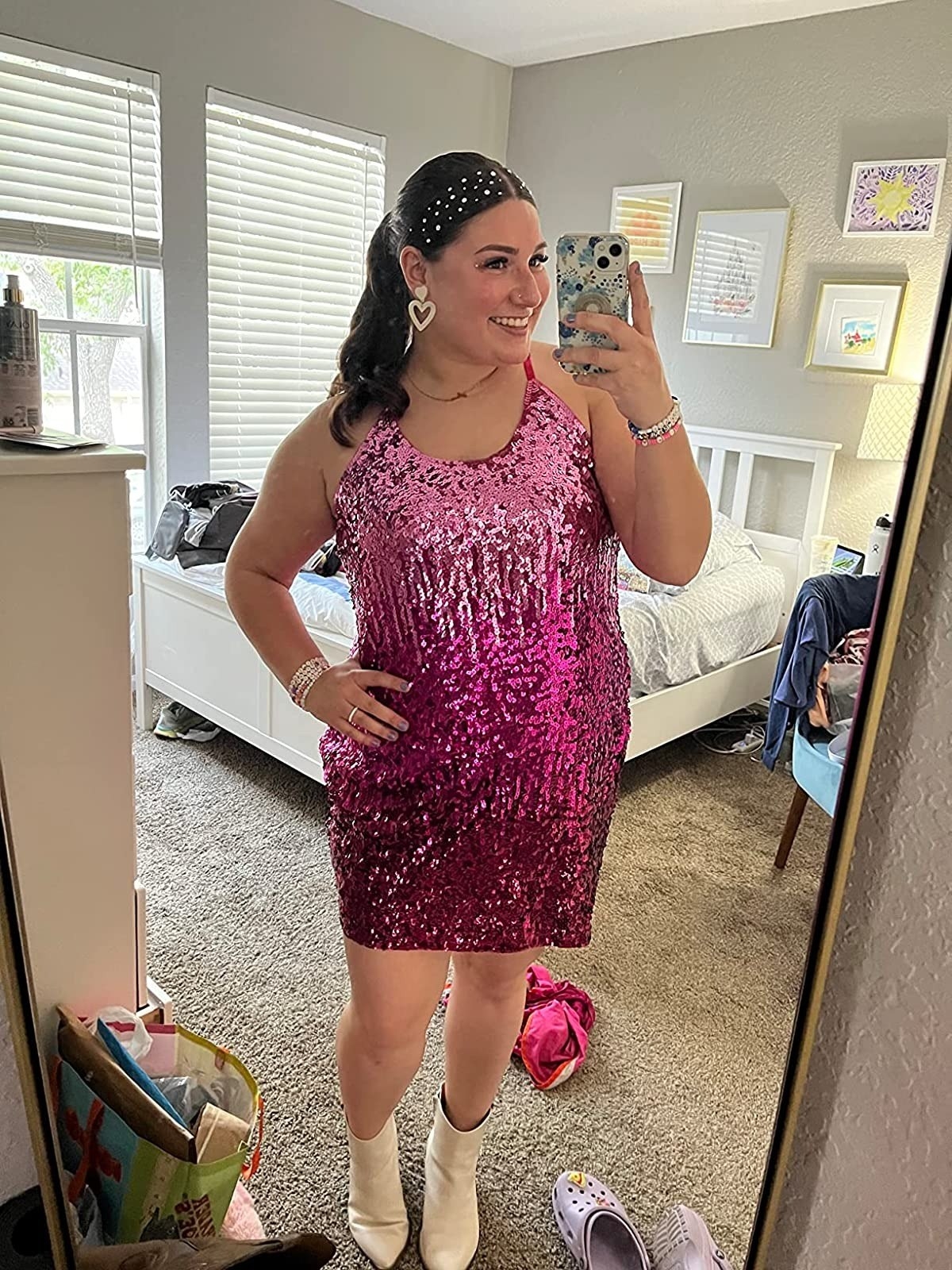reviewer wearing sleeveless sparkly pink sequin dress with white boots
