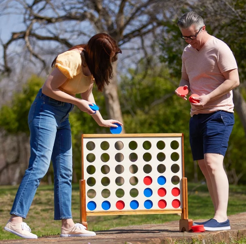 Two adults playing the four in a row game outdoors