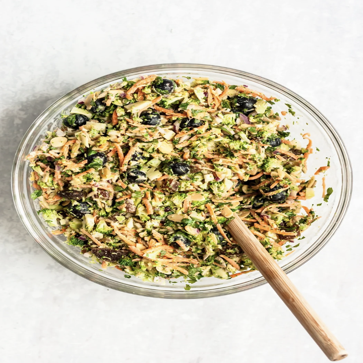 A bowl of broccoli salad with nuts and craisins.
