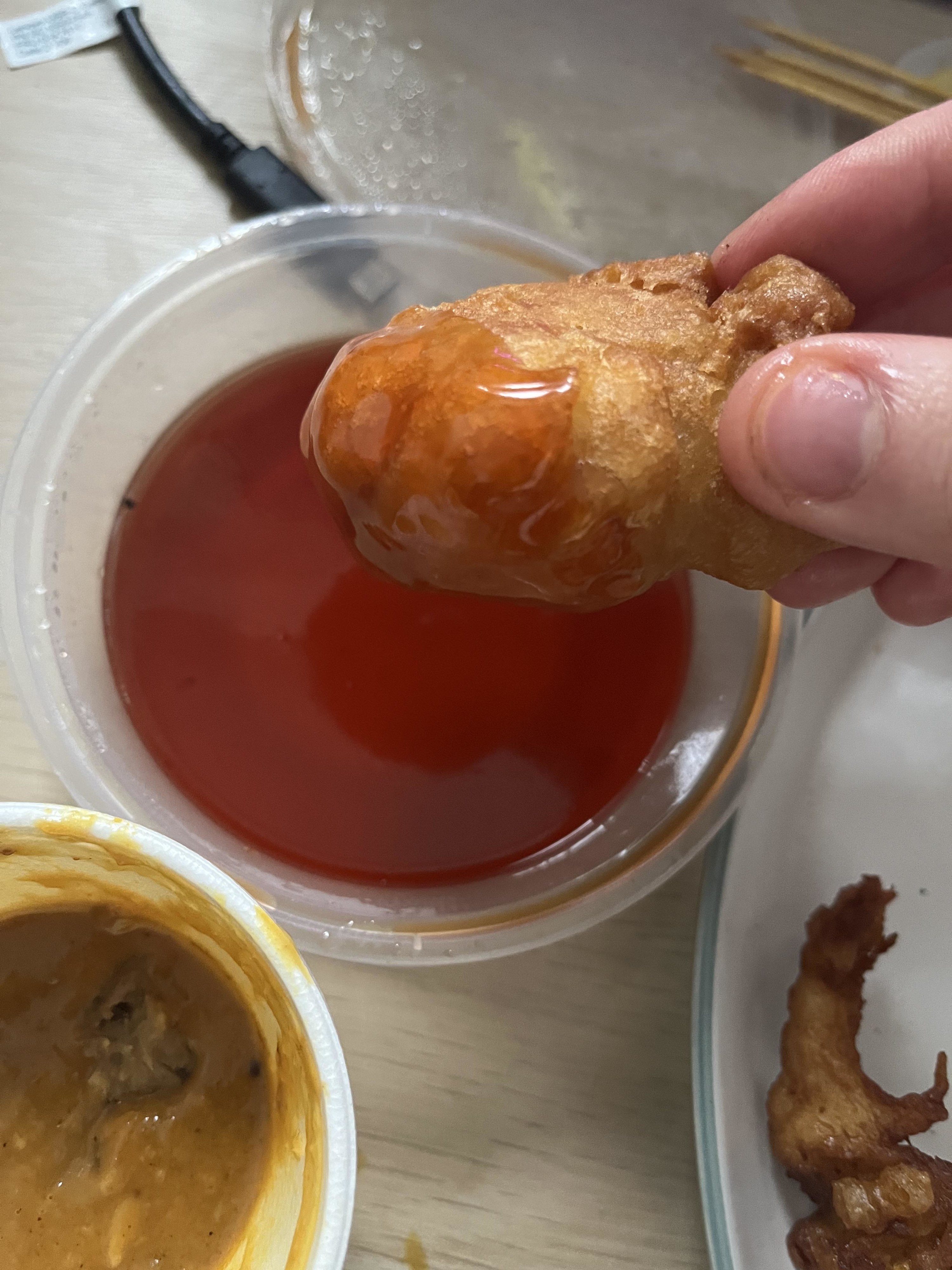 person dipping chicken ball into sweet and sour sauce