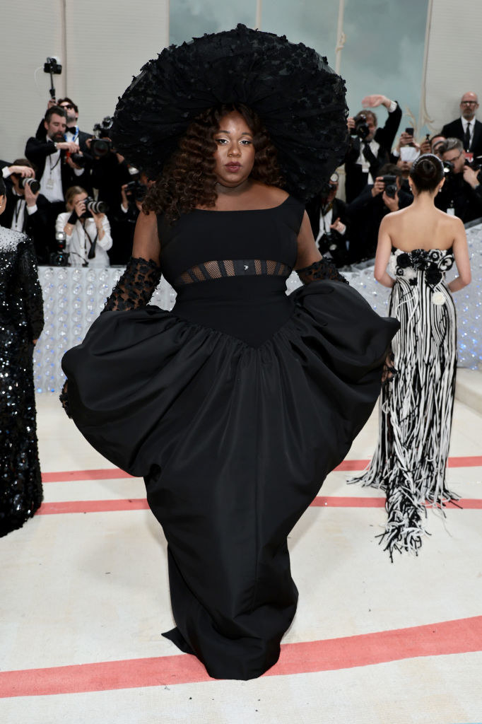 wearing a heart shaped dress with a very large hat