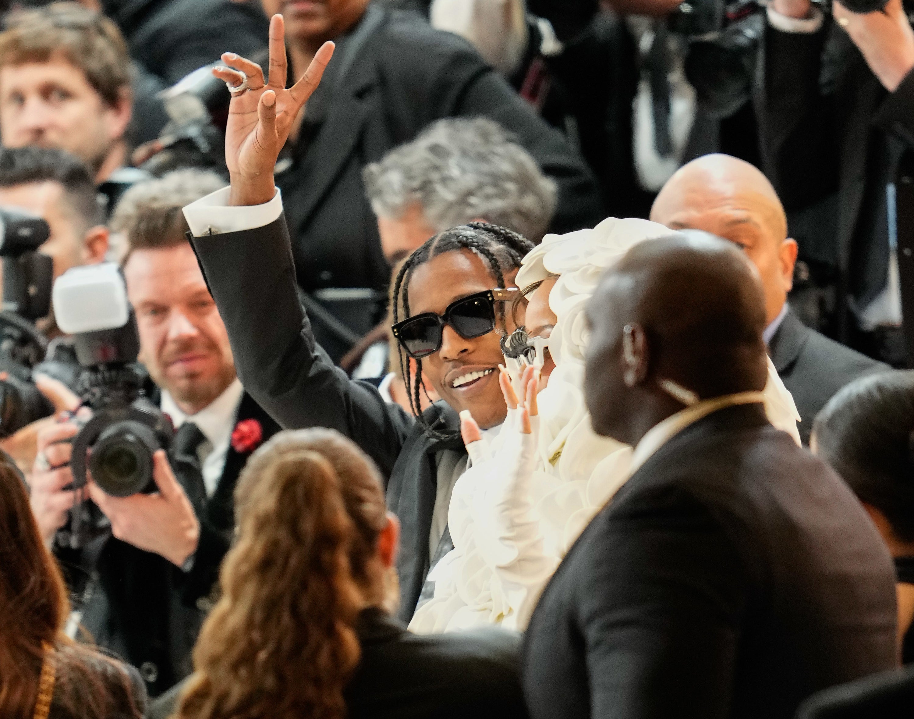 ASAP holds his hand up in the middle of a group of photographers