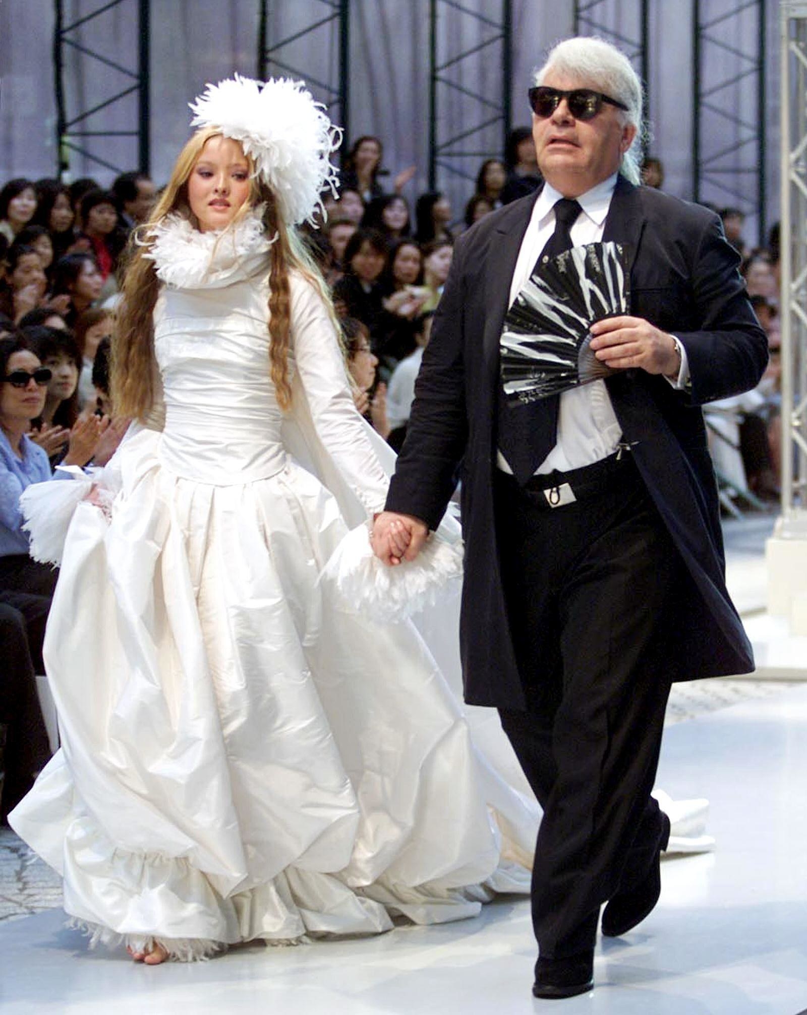 German designer Karl Lagerfeld of Chanel leads model Devon Aoki wearing a wedding dress during the autumn/winter 2000-2001 Chanel collection