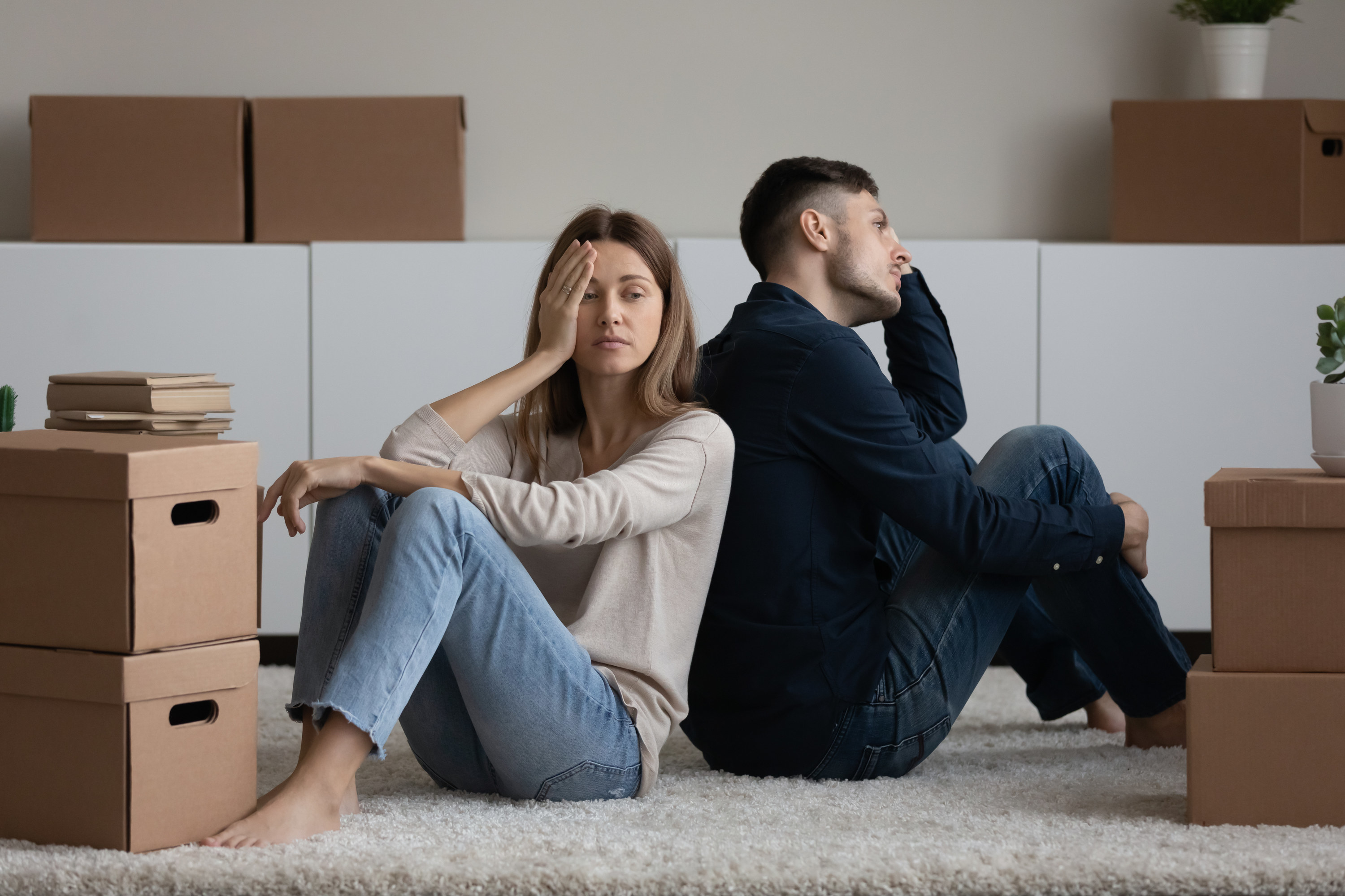 two unhappy people surrounded by moving boxes