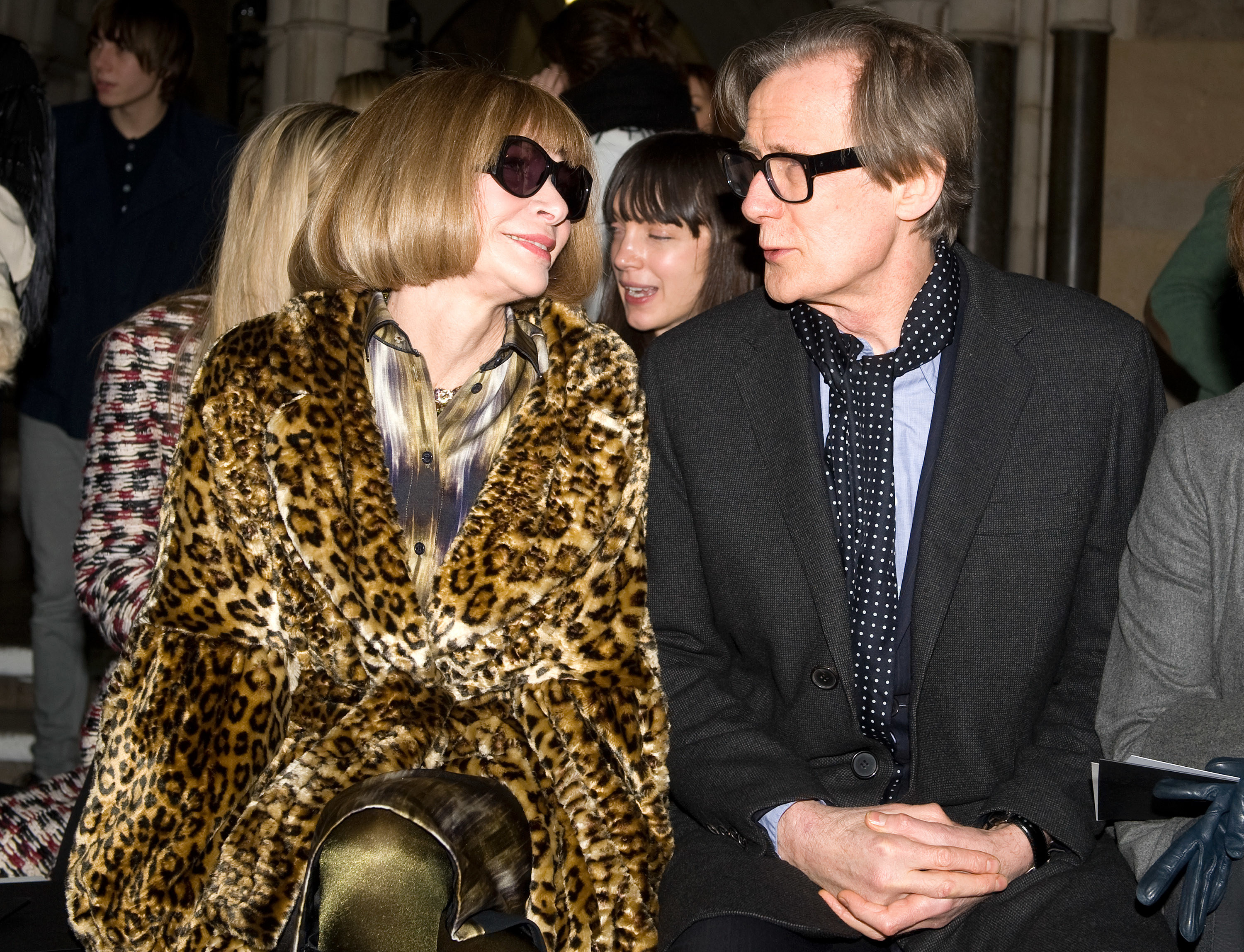 Anna and Bill sit side-by-side at a fashion show