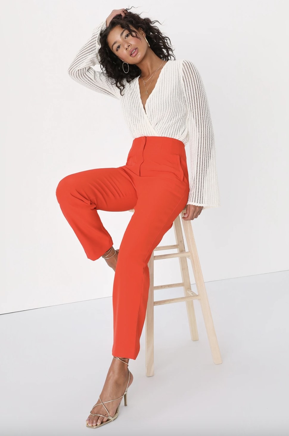 A model wearing the pants in a bright orange-red color