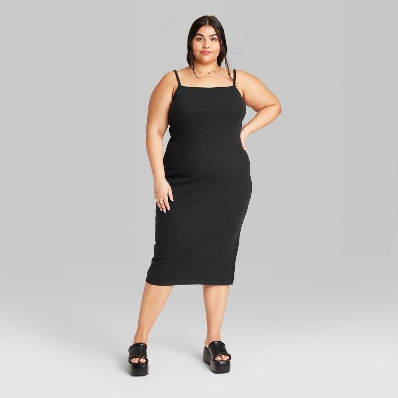 Model wearing black sleeveless bodycon mini dress with black sandals