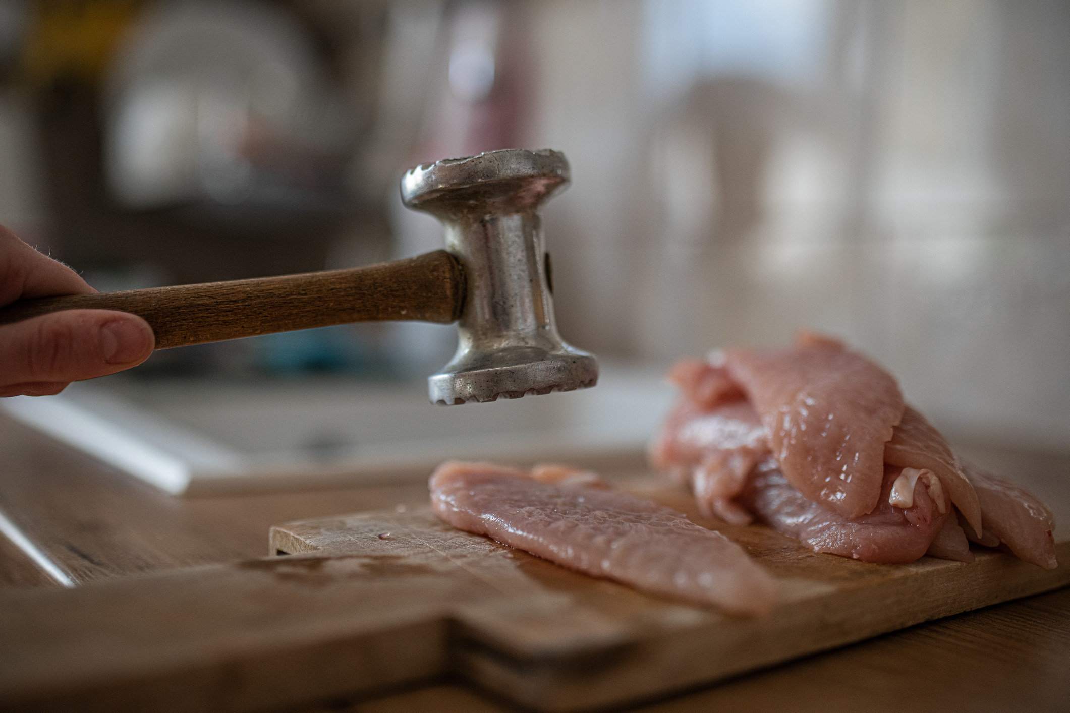 Someone tenderizing chicken