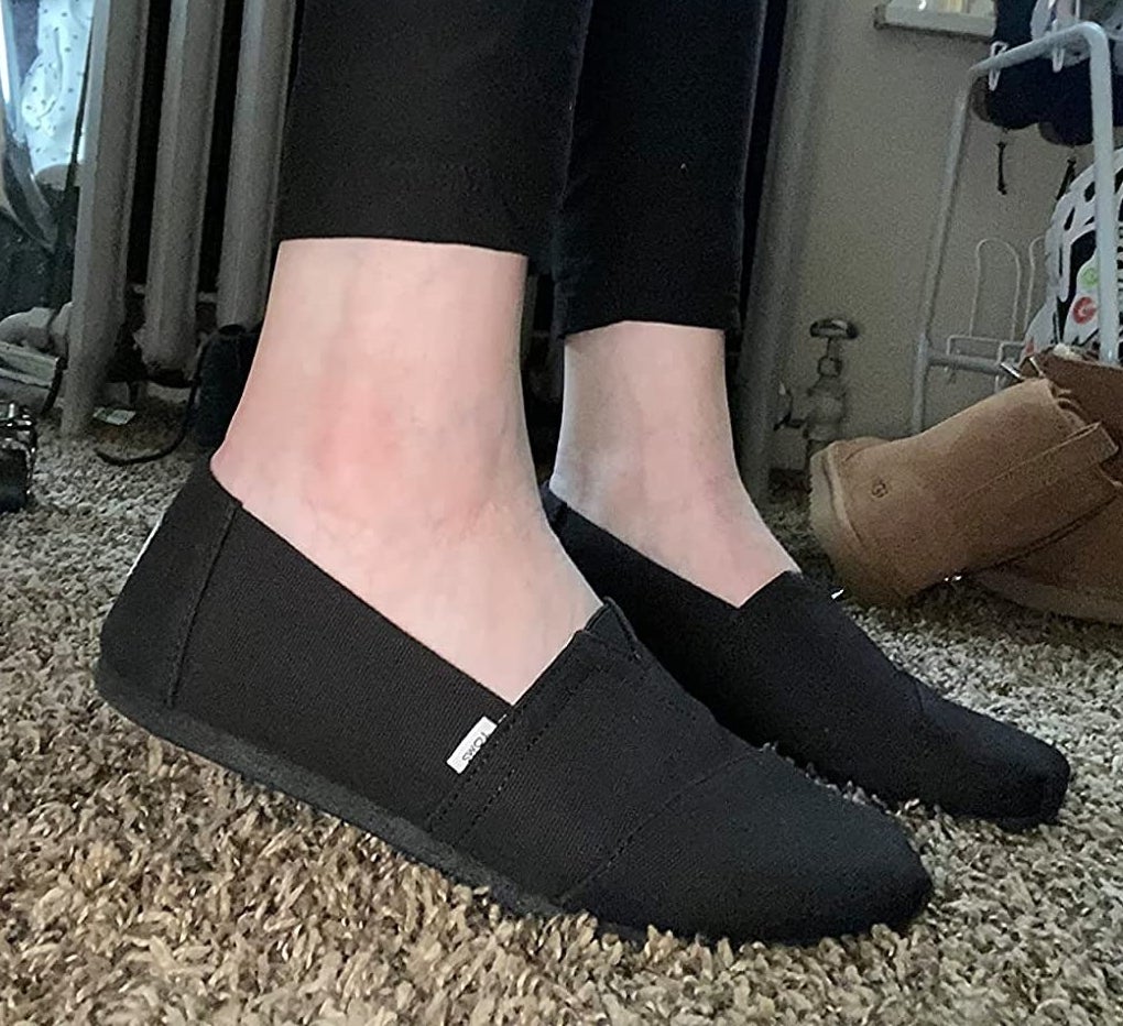 reviewer wearing black Toms canvas loafers
