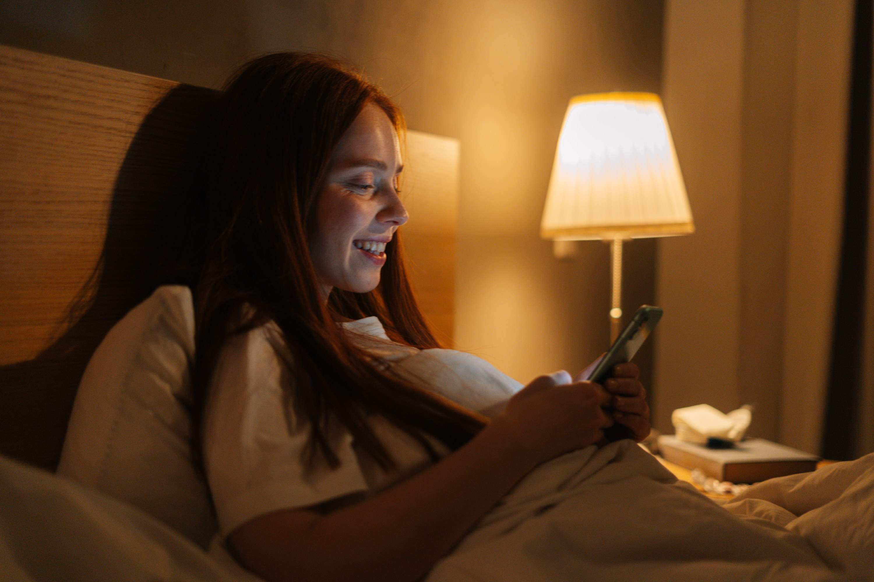 A woman texting on her phone in bed