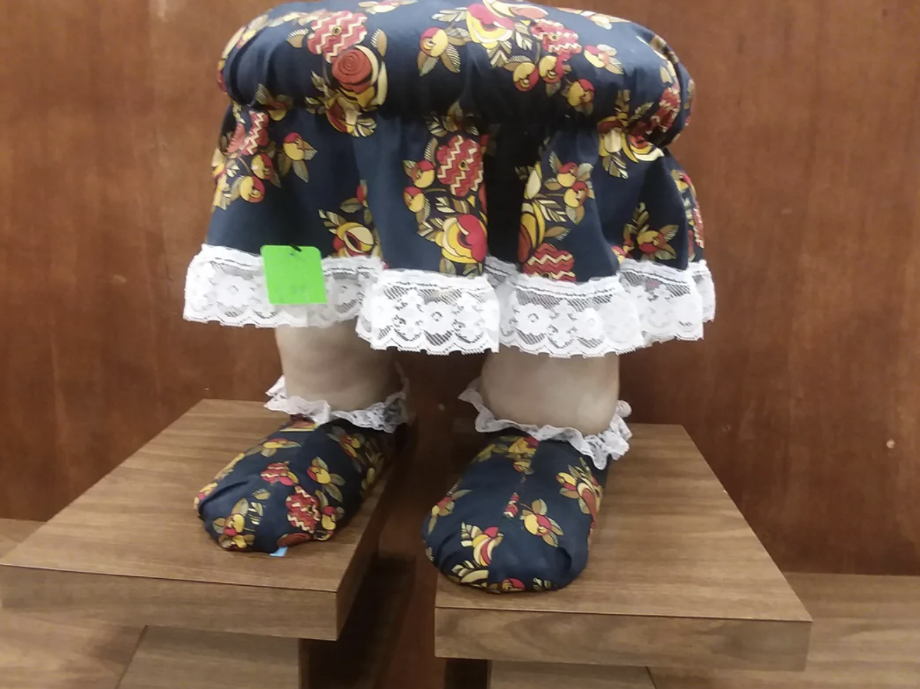 A footstool with a person&#x27;s legs as feet and a skirt as a cover