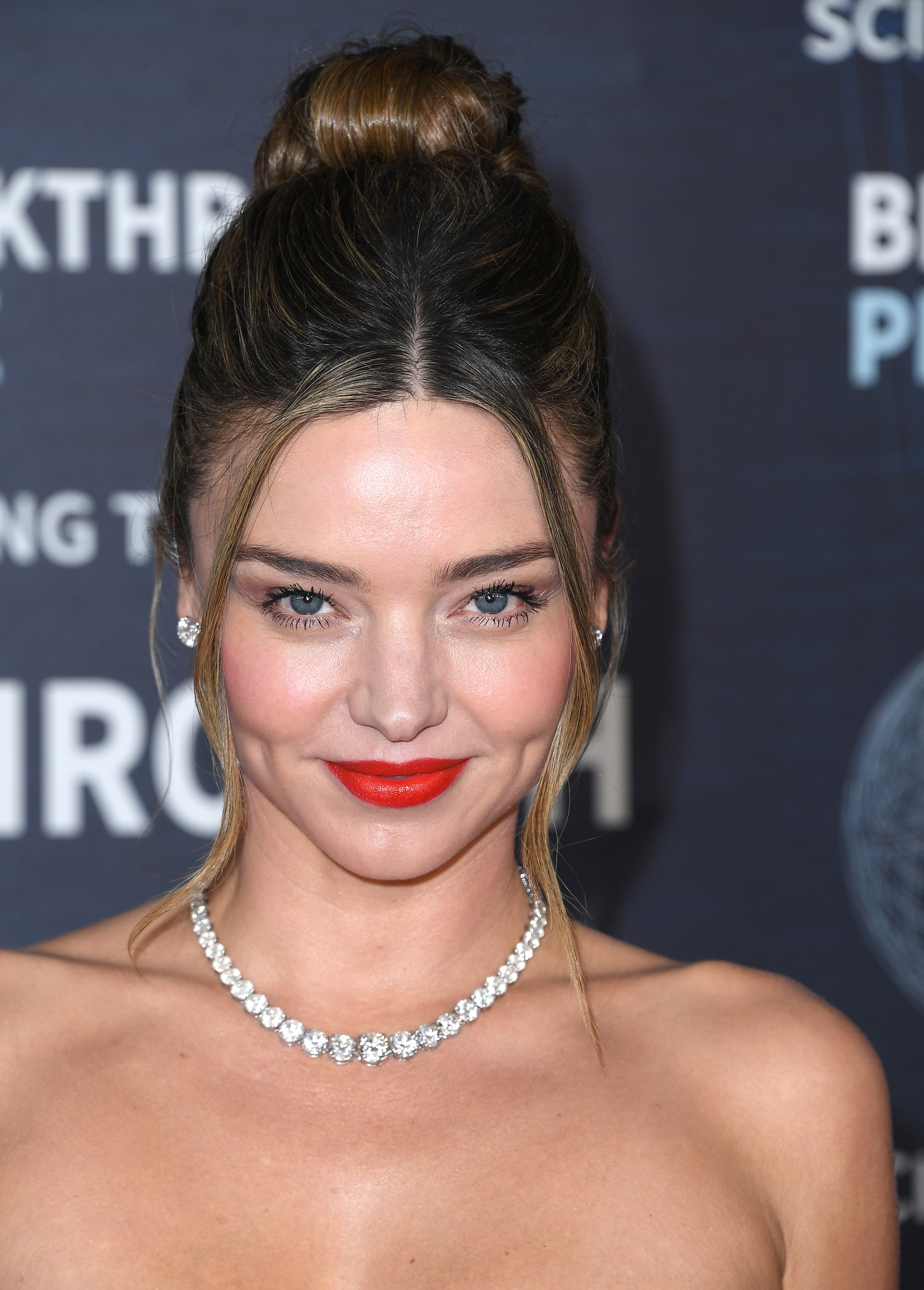 A close-up shot of Miranda Kerr on the red carpet in a strapless gown with a diamond necklace and bright red lips