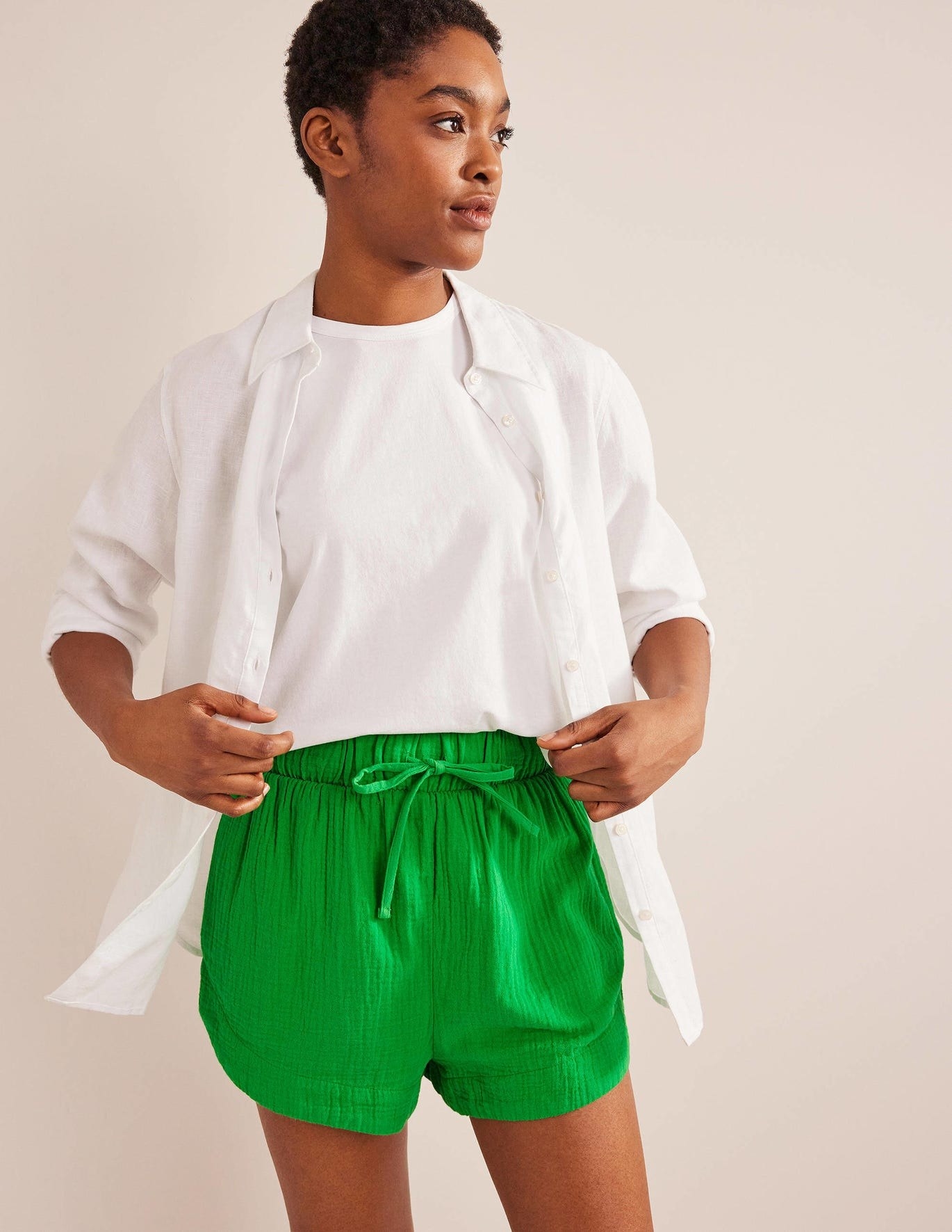 model in kelly green textured cheesecloth shorts with a tie waist styled with a white t-shirt and white button-up