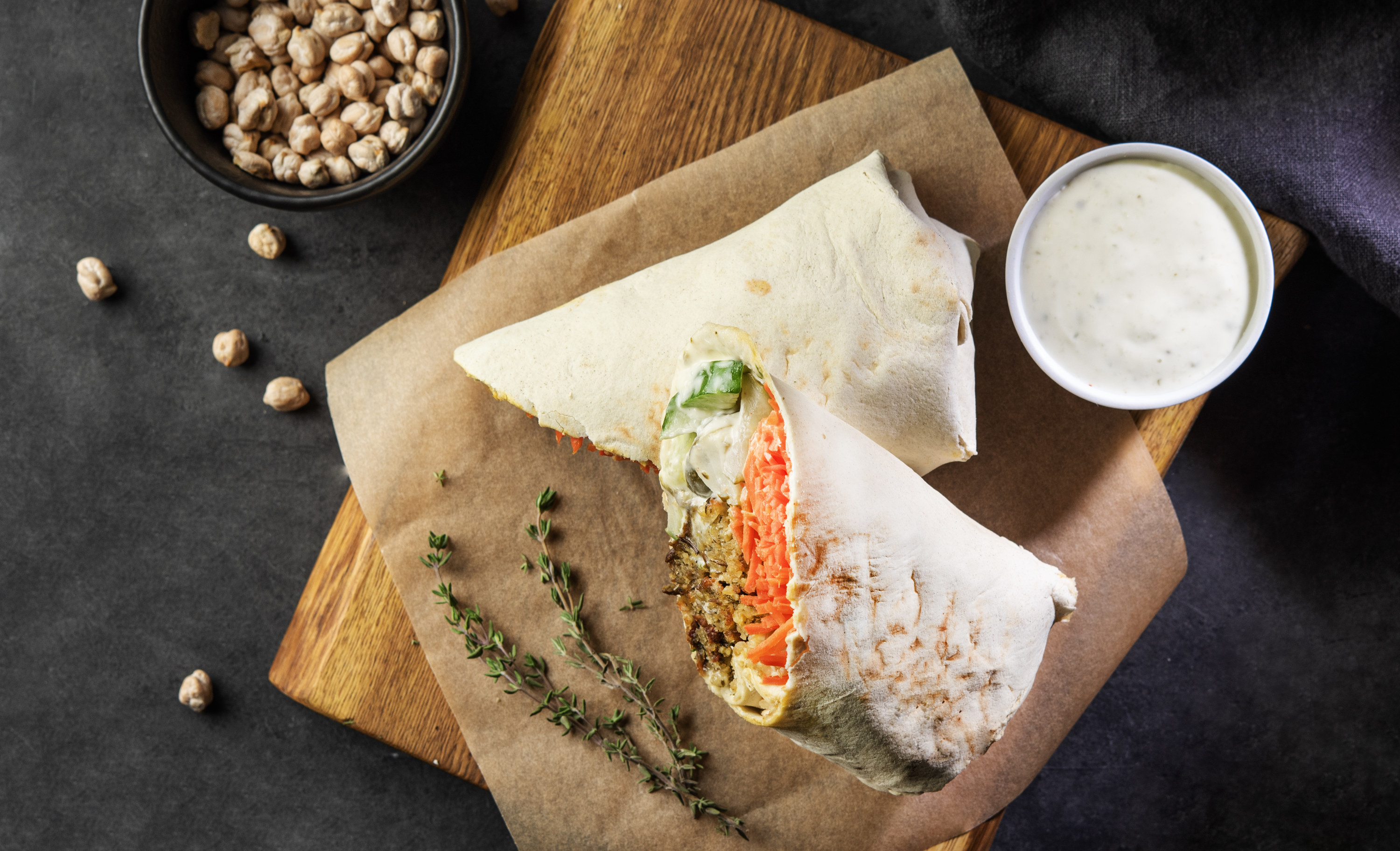 pita wrap filled with chickpeas and vegetables on wood serving board