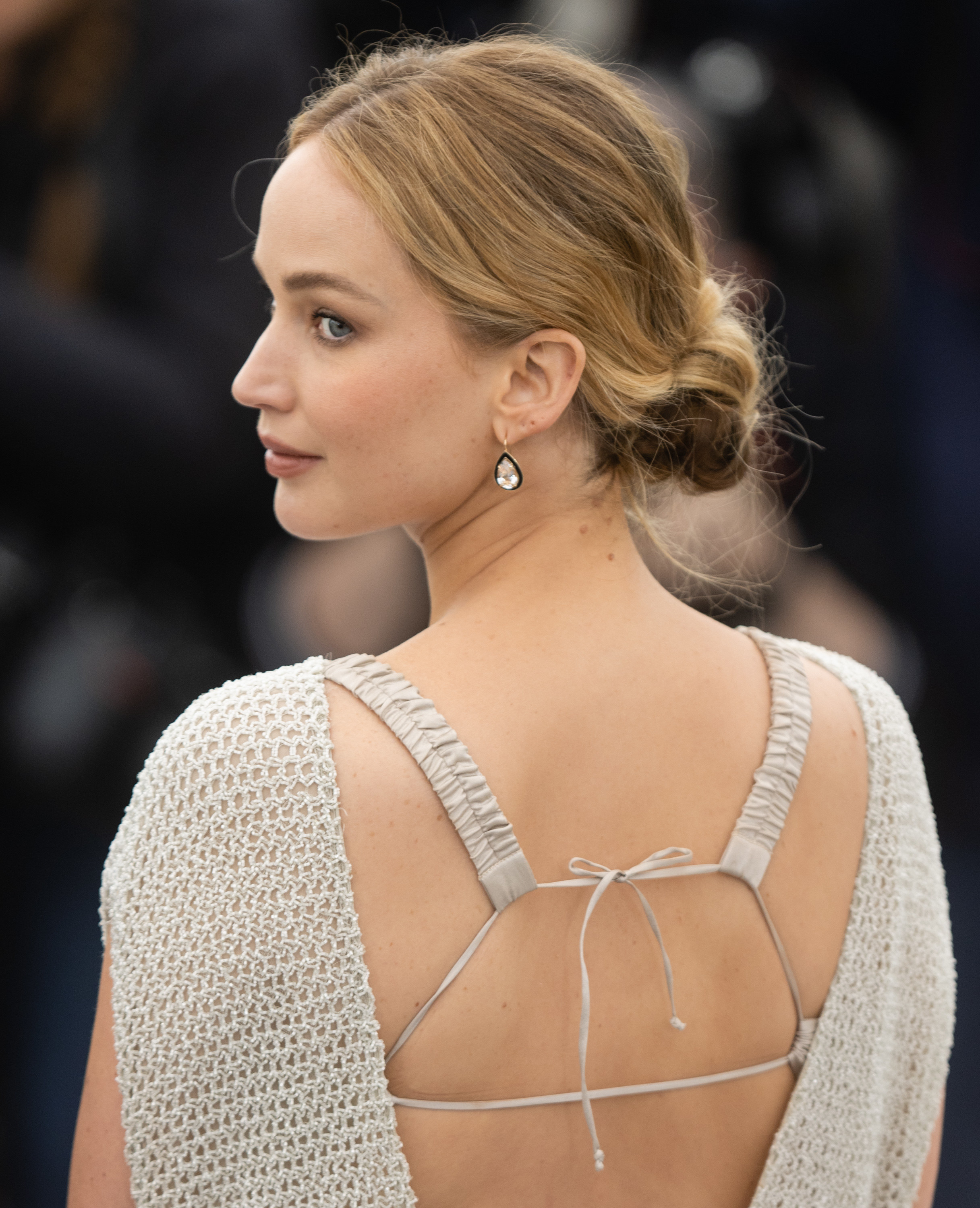 JLaw showing the exposed back of a sleeveless silver-gray gown