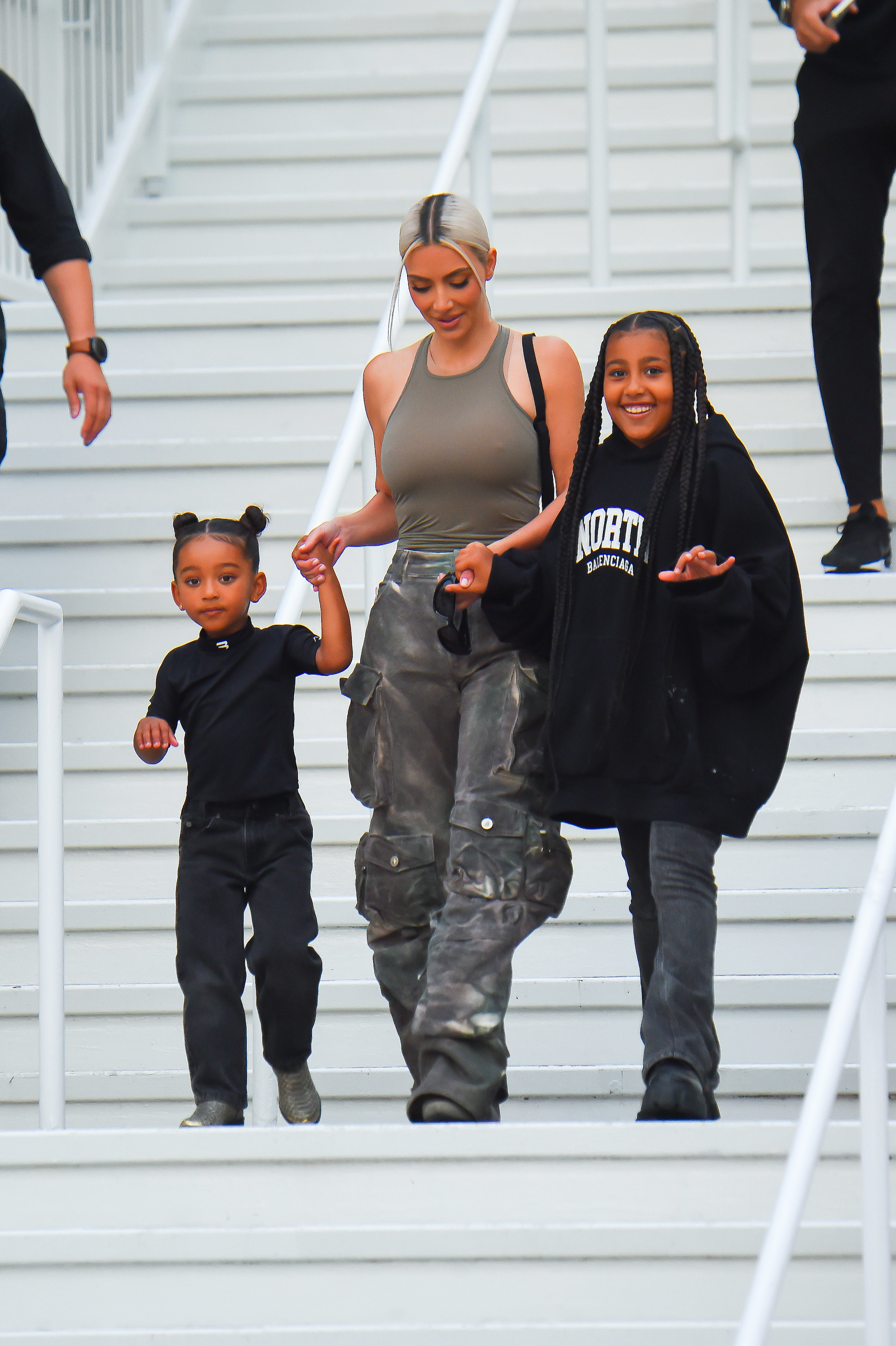 Kim holding the hands of two of her children on stairs