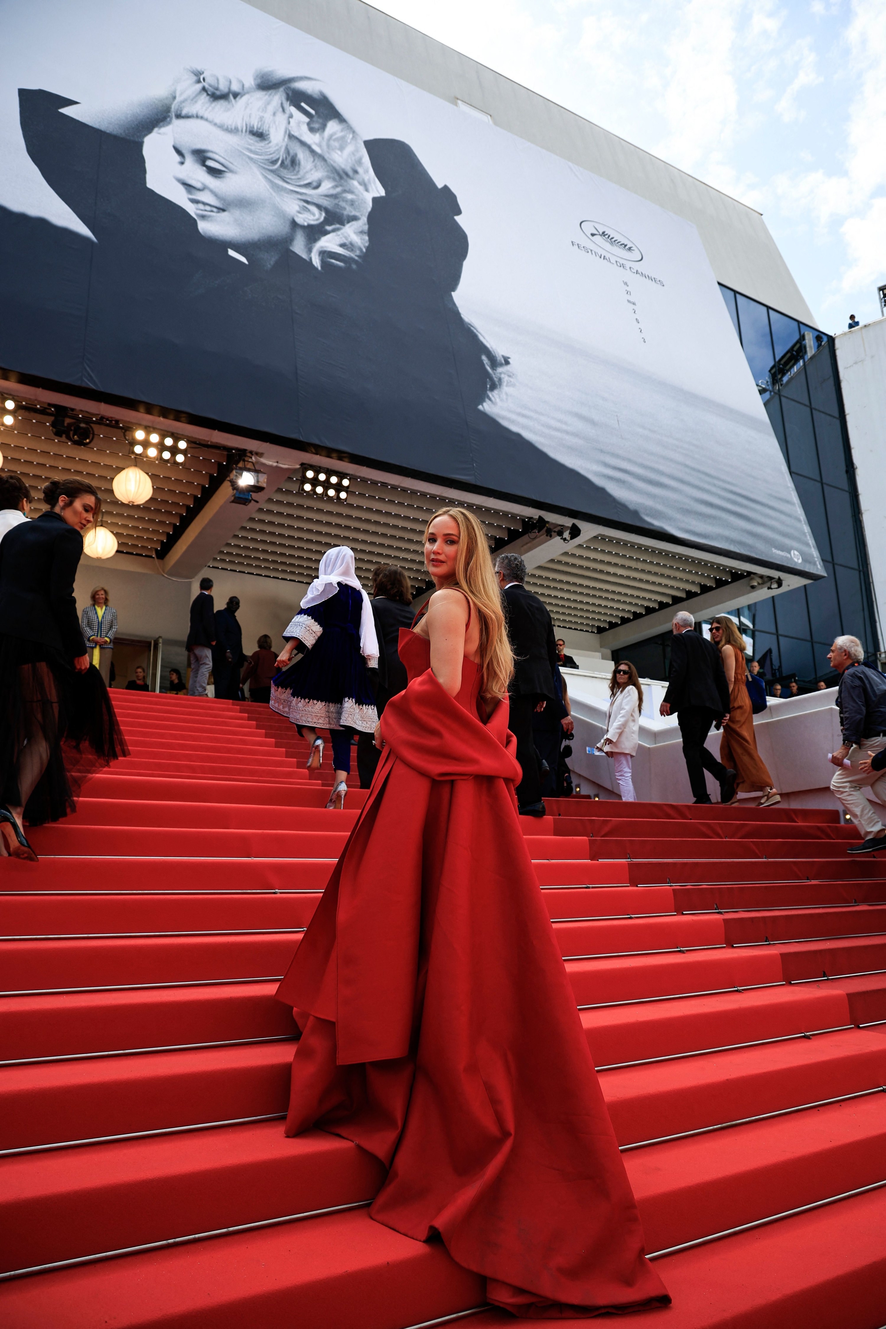 JLaw on the red carpet stairs in a spaghetti-strap red gown