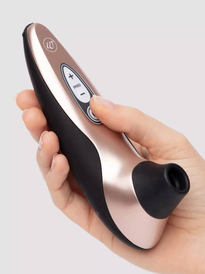 Hand holding rose gold and black clitoral vibrator