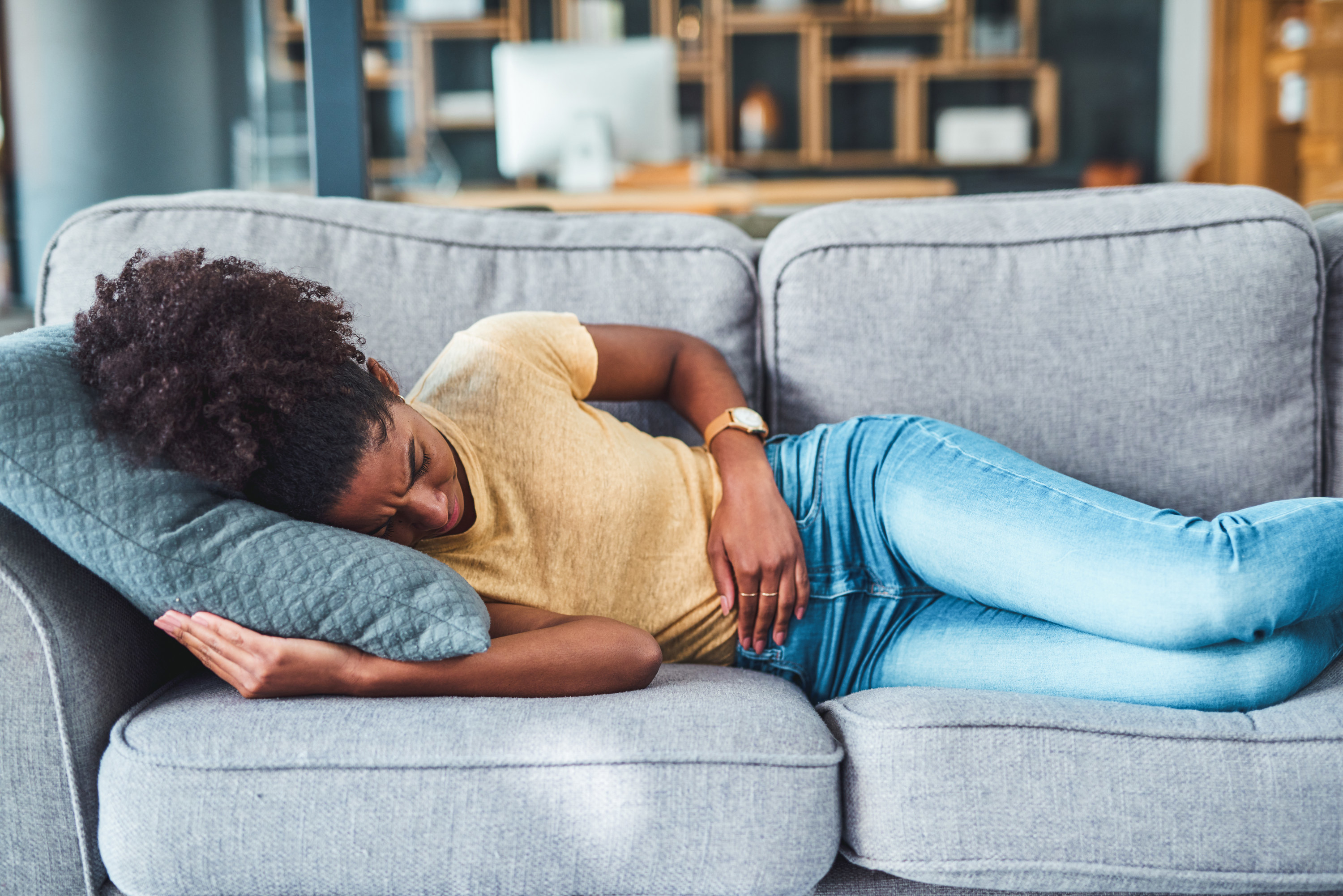 a woman with period pain on the couch