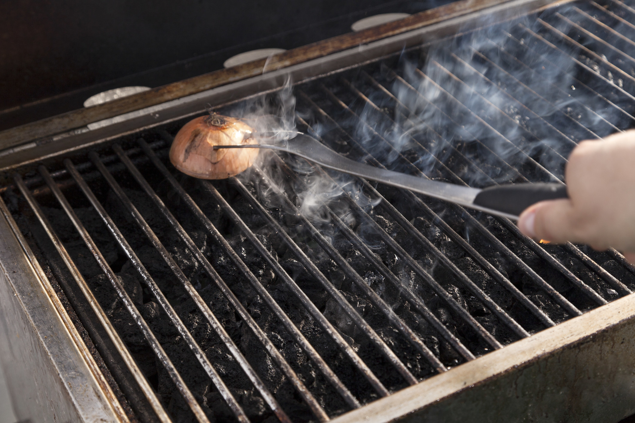 Cleaning a grill with a halved onion.