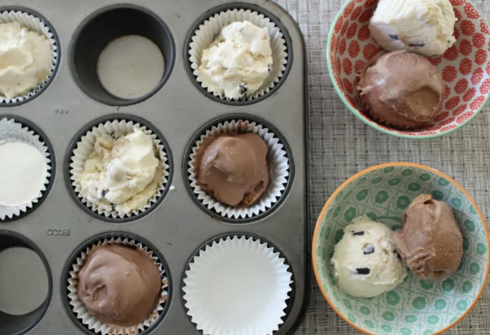 Ice cream scoops on cupcake liners in a muffin tin.
