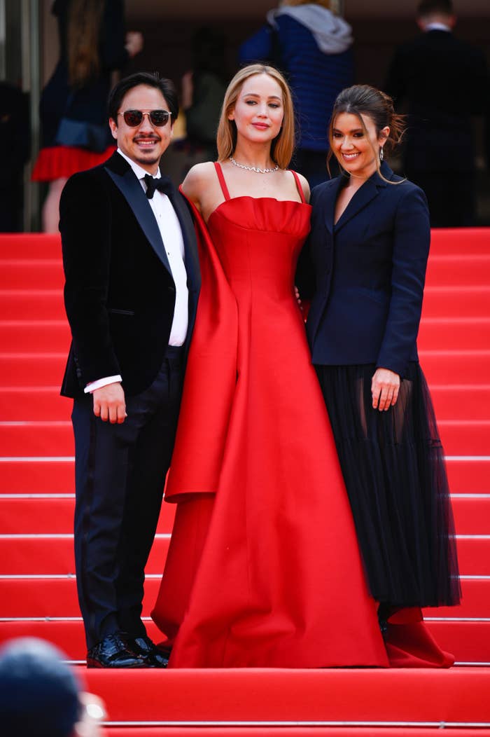 Jennifer Lawrence posing on the steps of the Cannes Film Festival with two people
