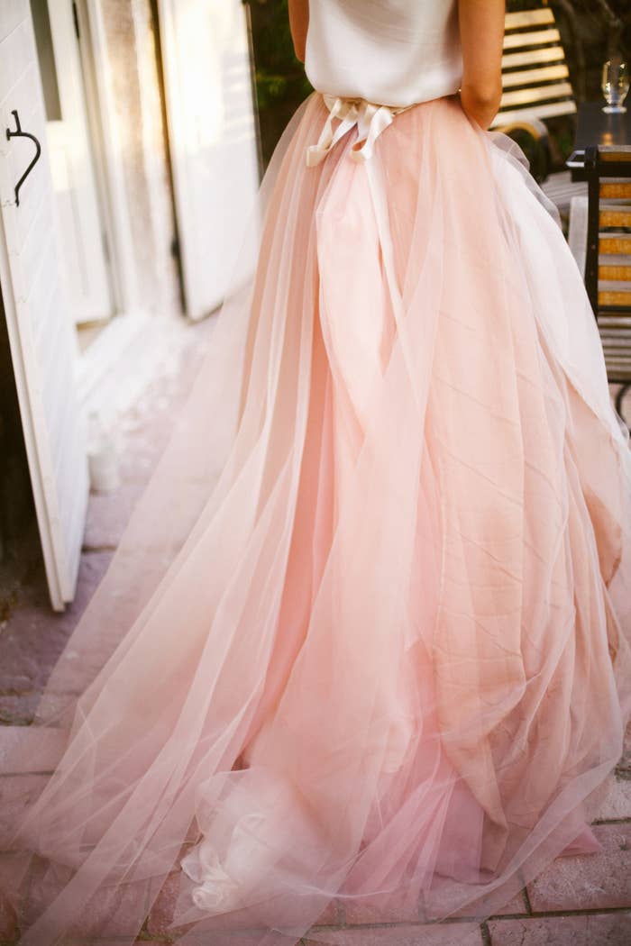 A bride walks in a pink tulle gown