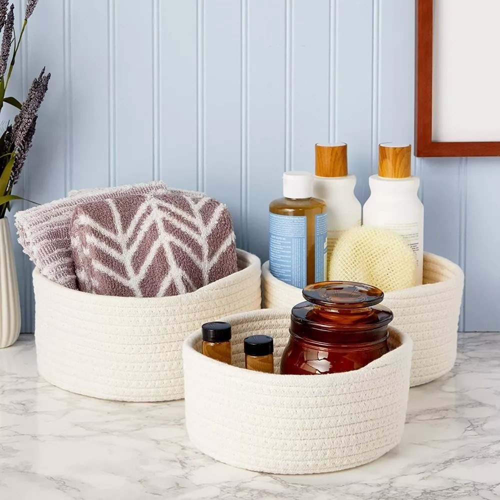 the three cream colored baskets holding various bathroom supplies