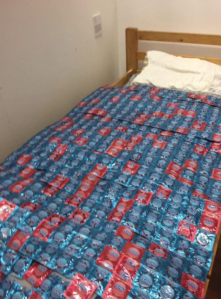 A bed with a bedspread made out of Durex condom packets