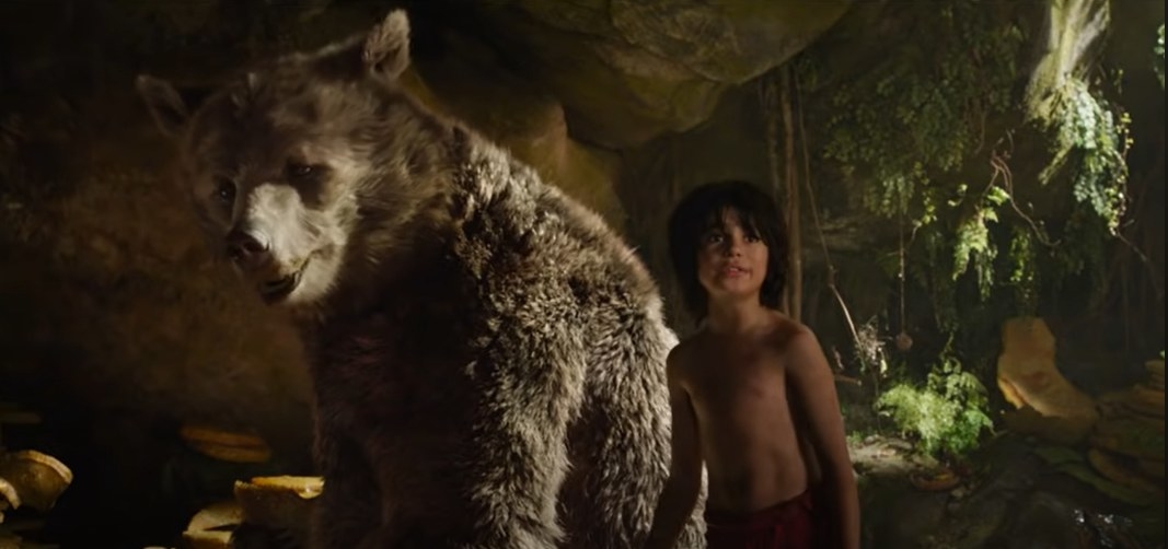 Young boy next to a large CGI bear in a cave setting, from the movie &quot;The Jungle Book&quot;