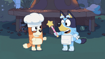 Bluey pointing a wand with a star at the top at Bingo while wearing an apron and Bingo is spinning while wearing a chef&#x27;s hat