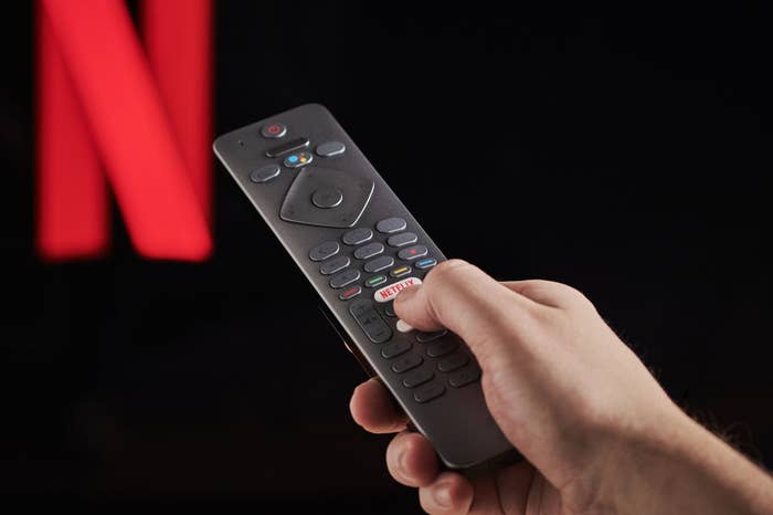 Someone holding a remote control navigating Netflix