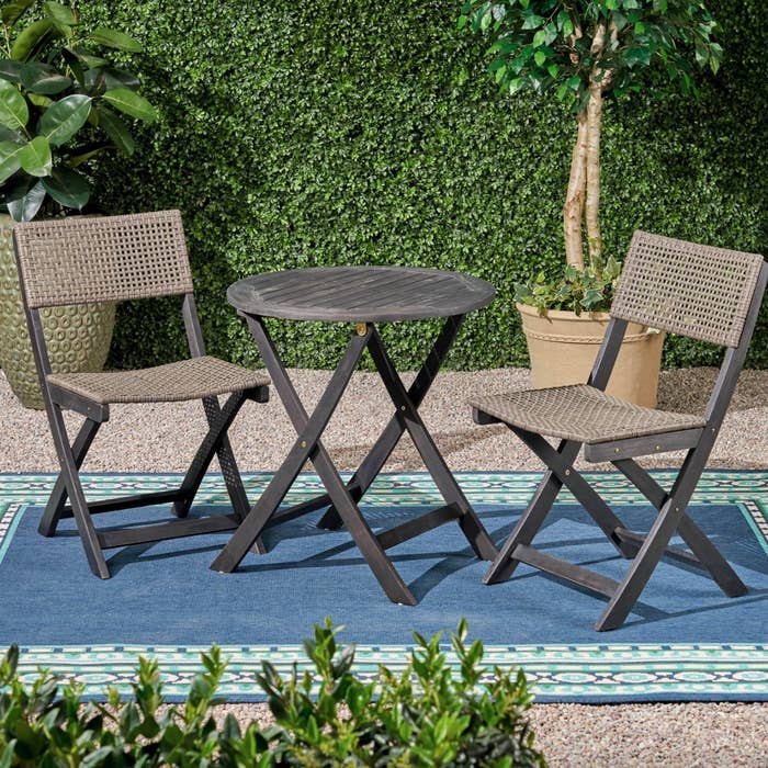 a grey-stained wooden outdoor set of table and chairs on a blue outdoor rug