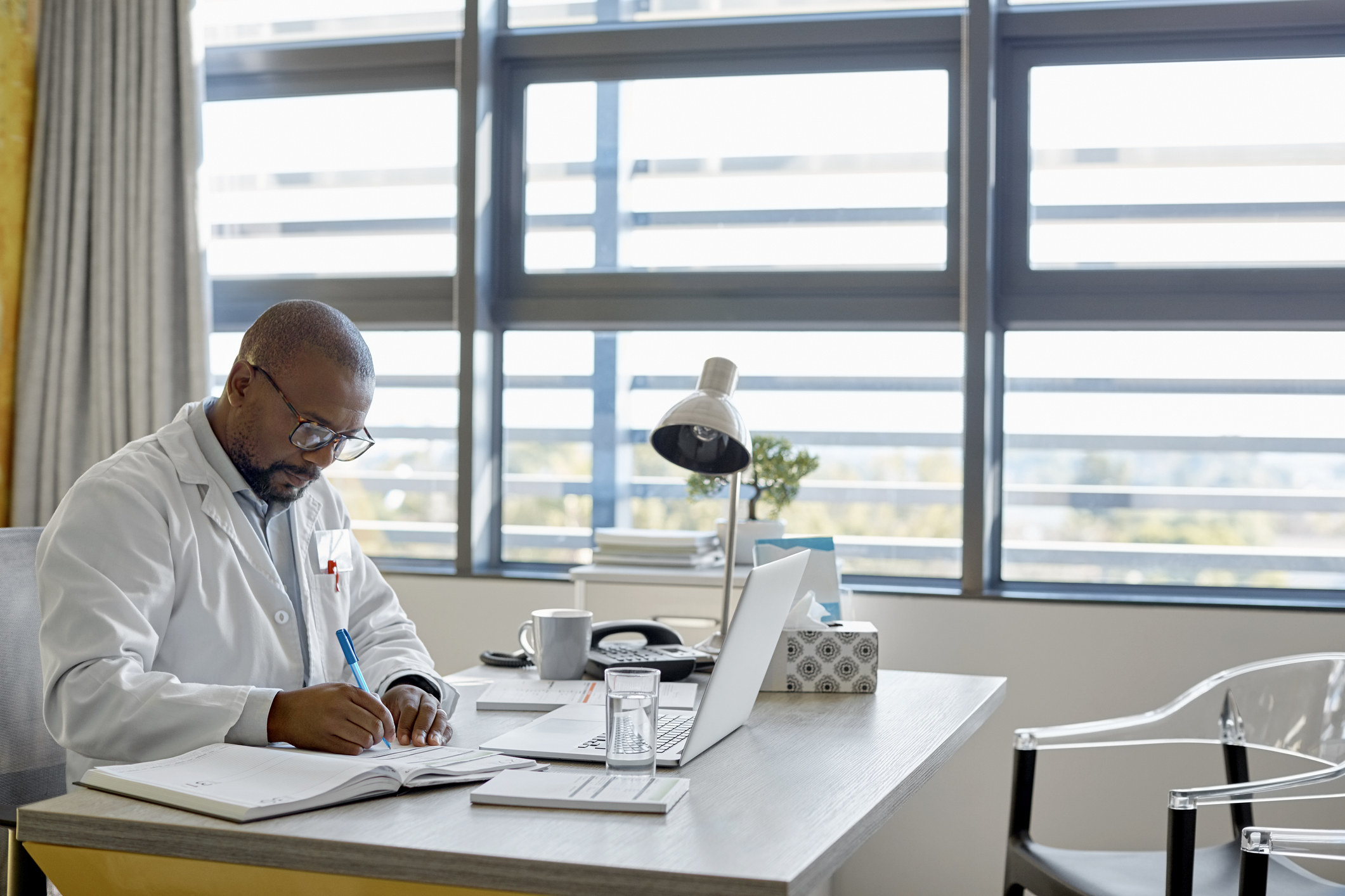 person sitting at their desk in a white coat