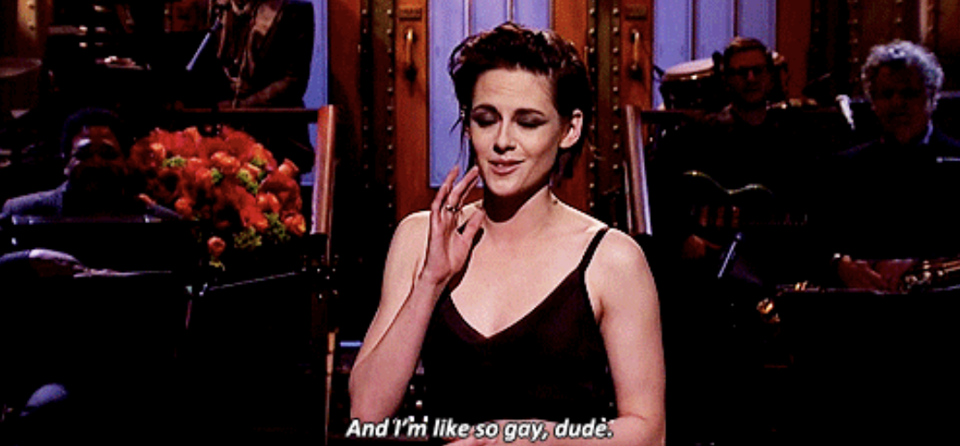 A screenshot of Kristen Stewart standing on the SNL monologue stage, with the caption &quot;And I&#x27;m, like, so gay, dude&quot;